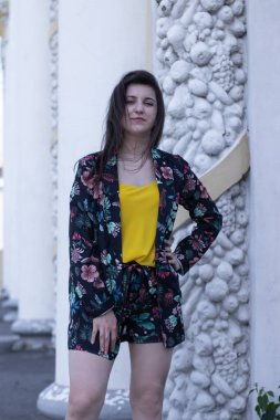 Sarı tişörtlü ve çiçekli şort kostümlü çekici esmer kadın. Boşluğu kopyala.