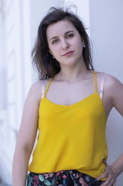 Sarı tişörtlü ve çiçekli şort kostümlü çekici esmer kadın. Boşluğu kopyala.