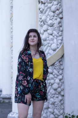 Sarı tişörtlü ve çiçekli şort kostümlü çekici esmer kadın. Boşluğu kopyala.