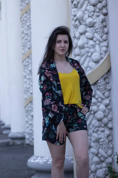 Attractive young brunette woman in yellow t-shirt and flowery shorts costume. copy space. — Stock Photo, Image