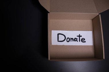 Kutuda siyah harflerle el yazısıyla yazılmış bir bağış yazısı. Bağış konsepti. Coronavirus salgınının içeriği. Boşluğu kopyala