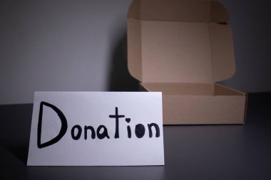 Bir kutunun yanında siyah harflerle el yazısıyla bağış tabelası. Bağış konsepti. Coronavirus salgınının içeriği
