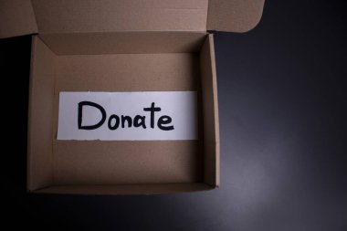 Kutuda siyah harflerle el yazısıyla yazılmış bir bağış yazısı. Bağış konsepti. Coronavirus salgınının içeriği. Boşluğu kopyala