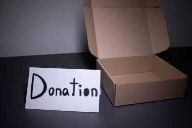 Bir kutunun yanında siyah harflerle el yazısıyla bağış tabelası. Bağış konsepti. Coronavirus salgınının içeriği