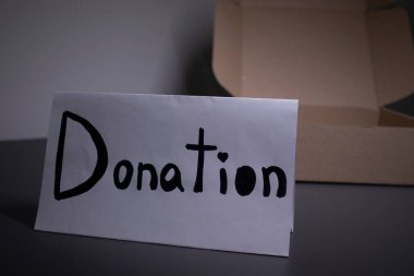 Bir kutunun yanında siyah harflerle el yazısıyla bağış tabelası. Bağış konsepti. Coronavirus salgınının içeriği