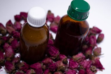 Küçük pembe güllerin yanında etiketsiz küçük sıvı şişeler. vücut bakımı ve güzellik konsepti. Boşluğu kopyala