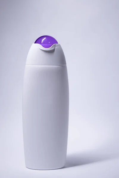 Біла пляшка шампуню з фіолетовою шиєю і без етикетки. догляд за тілом та концепція краси. Копіювати простір — стокове фото