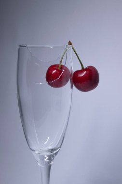 Beyaz arka planda kirazlı kırık bir şampanya bardağı. İzole edilmiş. Boşluğu kopyala.