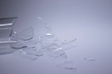 Kırık cam parçaları gri-beyaz arka plana saçılmış.