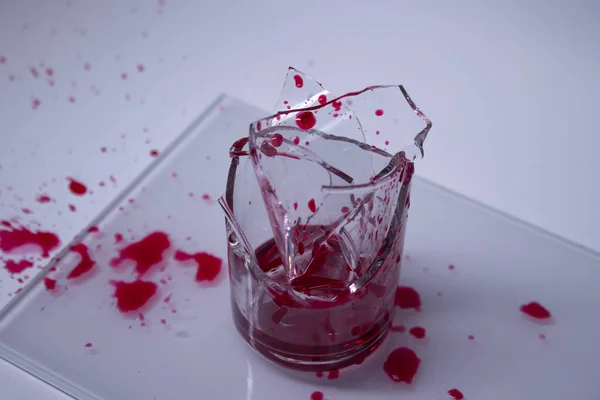 Gotas de líquido rojo sangre en los fragmentos de un vidrio roto sobre un fondo blanco. Aislado. Copiar espacio. concepto de dolor —  Fotos de Stock