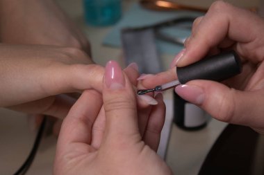 Manikür yapma süreci. Profesyonel manikürcünün elleri kapalı, oje sürüyor. Manikür ve tırnak temizliği kavramı. Güzellik konsepti Jel cilası, cila..