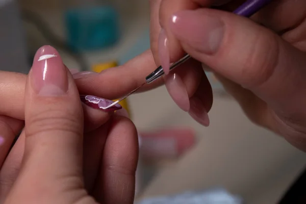 El proceso de hacer manicura. Primer plano de las manos de la manicura profesional, pintando pequeñas flores en las uñas. Concepto de hacer manicura. concepto de belleza. Esmalte de gel, goma laca . — Foto de Stock