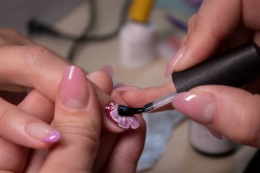 Manikür yapma süreci. Profesyonel manikürcünün elleri kapalı, oje sürüyor. Manikür ve tırnak temizliği kavramı. Güzellik konsepti Jel cilası, cila..