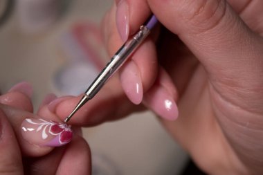 Manikür yapma süreci. Profesyonel manikürcünün elleri, tırnaklarına küçük taşlar takıyor. Manikür yapma kavramı. Güzellik konsepti Jel cilası, cila..