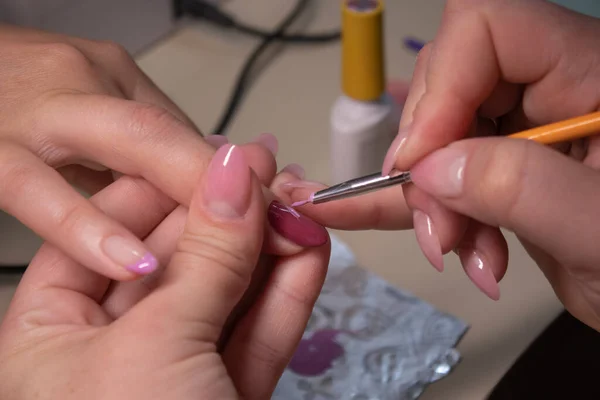 El proceso de hacer manicura. Primer plano de las manos de la manicura profesional, pintando pequeñas flores en las uñas. Concepto de hacer manicura. concepto de belleza. Esmalte de gel, goma laca . — Foto de Stock