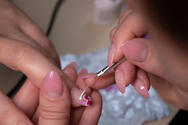 El proceso de hacer manicura. Primer plano de las manos de la manicura profesional, pintando pequeñas flores en las uñas. Concepto de hacer manicura. concepto de belleza. Esmalte de gel, goma laca . — Foto de Stock