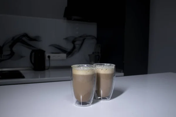 Dva šálky kávy v double-botoom skla na bílém stole v šedé kuchyni — Stock fotografie