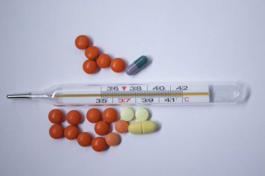 Beyaz arka planda bir sürü haplı cıva termometresi. Tıp ve hastalık konsepti. İzole edilmiş
