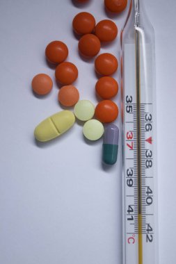 Beyaz arka planda bir sürü haplı cıva termometresi. Tıp ve hastalık konsepti. İzole edilmiş