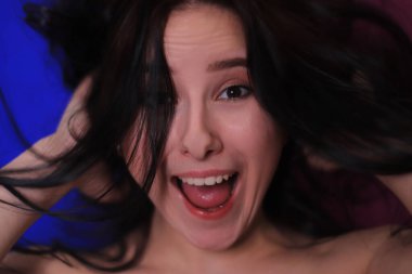 Mutlu esmer bir kızın pembe-mavi arka plandaki duygusal portresi.