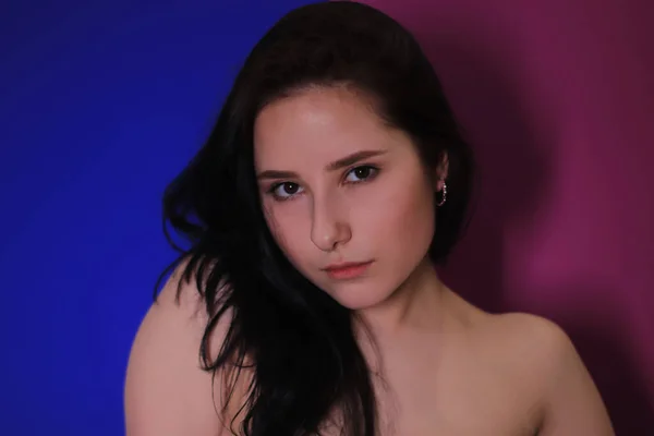 Kleurrijke emotionele pensive portret van een brunette meisje op een roze-blauwe achtergrond — Stockfoto