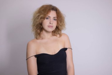 Siyah fanilalı, kıvırcık, sarışın, güzel bir kızın duygusal portresi.