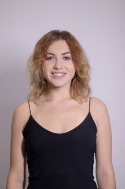 Siyah fanilalı, kıvırcık, sarışın, güzel bir kızın duygusal portresi.