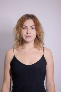 Siyah fanilalı, kıvırcık, sarışın, güzel bir kızın duygusal portresi.