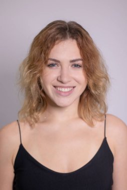 Siyah fanilalı, kıvırcık, sarışın, güzel bir kızın duygusal portresi.