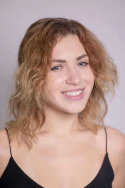 Emotional portrait of a beautiful curly blonde-redhead in black undershirt — Stock Photo, Image