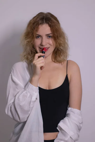 Hermosa rubia rizada en camiseta negra y camisa blanca sexy aplica lápiz labial rojo —  Fotos de Stock