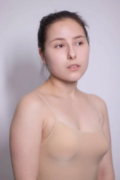 El retrato emocional de la morena atractiva, la actriz en la camiseta de color beige - el traje de cuerpo sobre el fondo blanco. espacio para texto — Foto de Stock