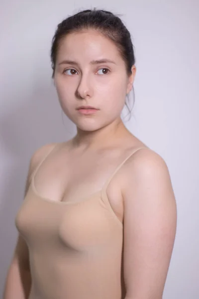 Retrato emocional de morena atraente, atriz em uma camiseta bege - bodysuit em fundo branco. espaço para texto — Fotografia de Stock