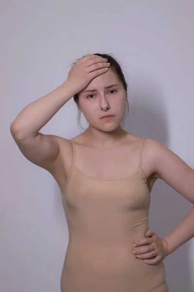Συναισθηματική πορτρέτο της ελκυστική μελαχρινή, ηθοποιός σε ένα μπεζ φανελάκι - bodysuit σε λευκό φόντο. χώρος για κείμενο — Φωτογραφία Αρχείου