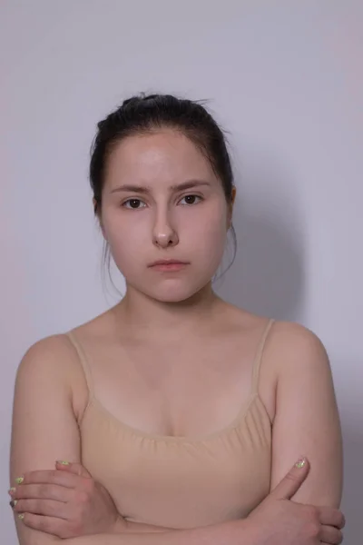 Συναισθηματική πορτρέτο της ελκυστική μελαχρινή, ηθοποιός σε ένα μπεζ φανελάκι - bodysuit σε λευκό φόντο. χώρος για κείμενο — Φωτογραφία Αρχείου