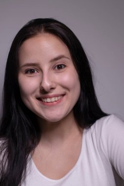 Açık tenli, doğal makyajlı güzel bir esmerin kapalı bir portresi. Kozmetik konsepti. gri arkaplanda
