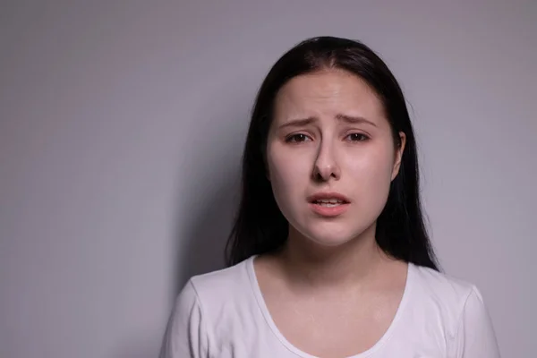 Retrato de uma jovem triste e deprimida. sobre fundo cinzento. conceito de pessoas nervosas e perturbadas — Fotografia de Stock