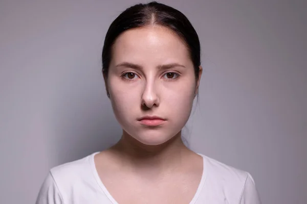 Портрет грустной и подавленной молодой женщины. на сером фоне. нервные и расстроенные люди — стоковое фото