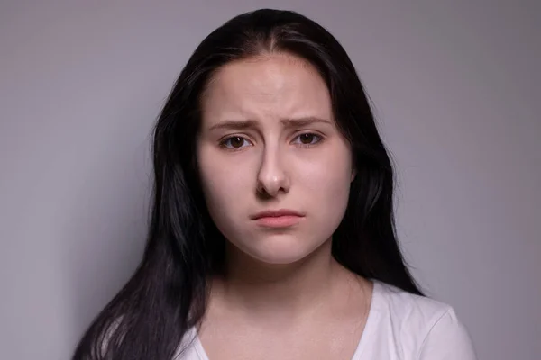 Πορτρέτο της θλιμμένης και καταθλιπτικής νεαρής γυναίκας. σε γκρι φόντο. νευρικό και αναστατωμένος άνθρωποι έννοια — Φωτογραφία Αρχείου