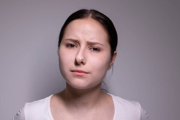 portrait of pensive thoughtful girl, looking seriously brunette. on grey background with copy space. lifestyle concept