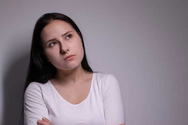 portrait of pensive thoughtful girl, looking seriously brunette. on grey background with copy space. lifestyle concept