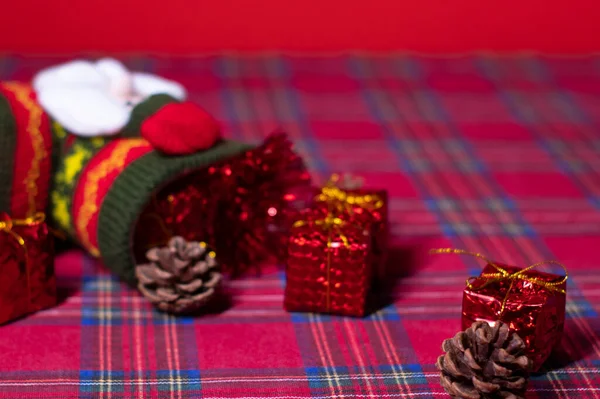 Weihnachtsdekoration auf rotem Hintergrund: Spielzeuggeschenke und Tannenzapfen und Socken mit dem Weihnachtsmann. 2021 Neujahrsthema. Vorlage für Postkarten — Stockfoto