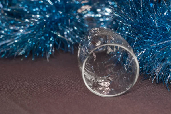 在香槟酒杯中的订婚戒指，靠近蓝色闪亮的金银花，用来装饰圣诞树。新年建议主题 — 图库照片