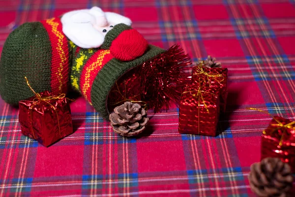 Weihnachtsdekoration auf rotem Hintergrund: Spielzeuggeschenke und Tannenzapfen und Socken mit dem Weihnachtsmann. 2021 Neujahrsthema. Vorlage für Postkarten — Stockfoto