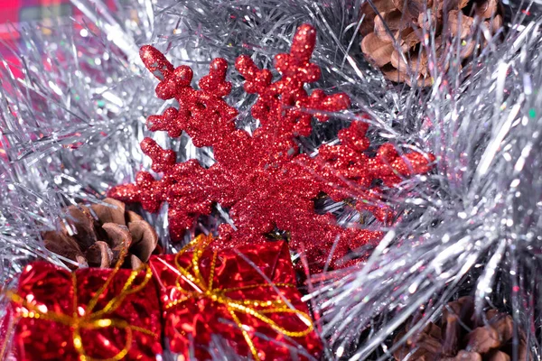 Las decoraciones de Año Nuevo - los regalos rojos, los conos y los copos de nieve en el oropel plateado para el árbol de Navidad — Foto de Stock