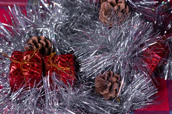 Dekoracje noworoczne - czerwone prezenty, szyszki i płatki śniegu w srebrnym świecidełku na choinkę — Zdjęcie stockowe