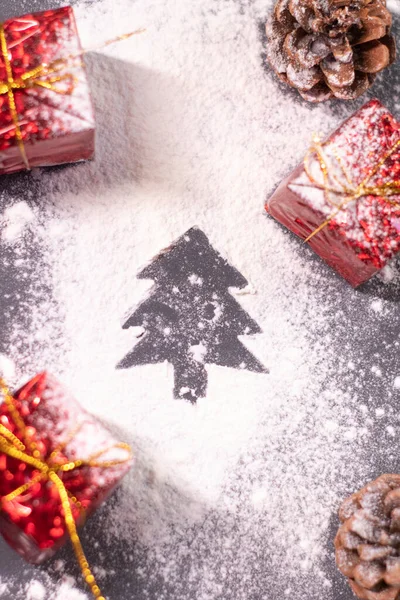 Decorazioni natalizie, regali e pigne nella neve e la silhouette di un albero di Natale. L'umore natalizio. Foto flatly — Foto Stock