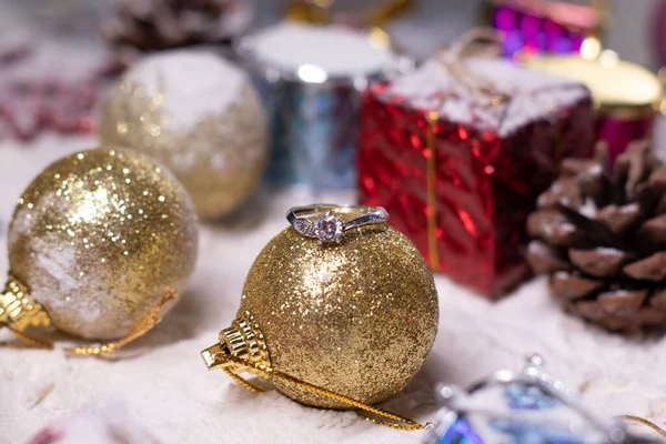 Ασημένια κοσμήματα δαχτυλίδι αρραβώνων δίπλα στη διακόσμηση της Πρωτοχρονιάς στο χιόνι. Χριστουγεννιάτικα δέντρα, μπάλες, νιφάδες χιονιού, δώρα, κώνους. Χριστουγεννιάτικη διάθεση. Τυφλή φωτογραφία — Φωτογραφία Αρχείου