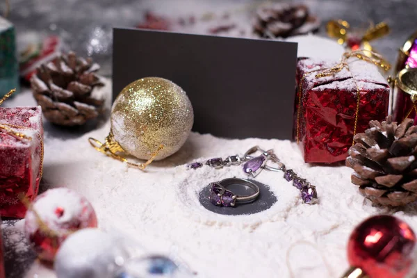 紫色珠宝- -戒指和耳环- -在雪地里仅次于新年装饰品。圣诞树，球，雪花，礼物，球果。圣诞气氛。平淡的照片 — 图库照片