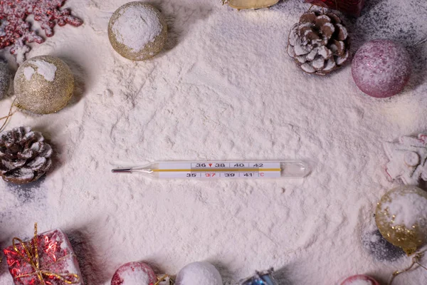 medical thermometer next to New Years decorations in the snow. snowflakes, gifts, cones. Christmas mood. Flatly photo